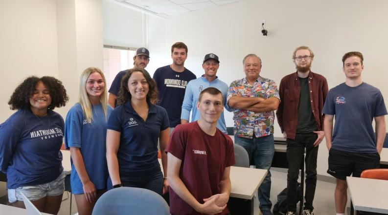 A group of students stand in a classroom.